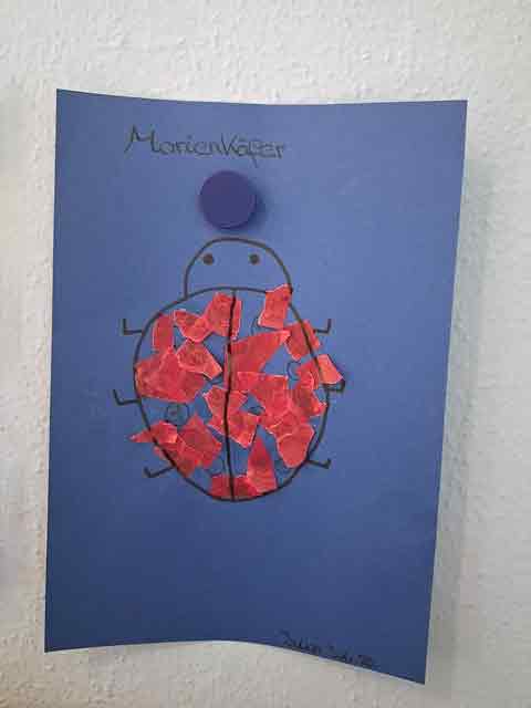 von den Kükenkindern aus Papierschnipseln geklebter Marienkäfer