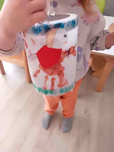 Ein KrippenkInd hält eine bemalte Laterne in der Hand