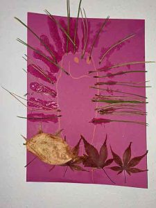 Igelbild mit Kiefernadeln und Blättern auf farbigem Papier gestaltet