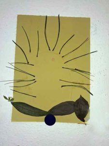 Igelbild mit Kiefernadeln und Blättern auf farbigem Papier gestaltet
